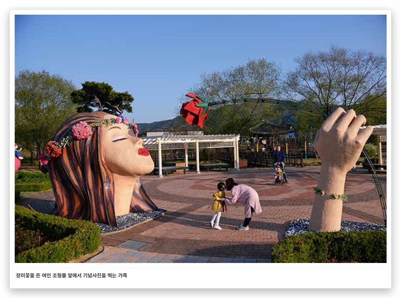장미꽃을 든 여인 조형물 앞에서 기념사진을 찍는 가족