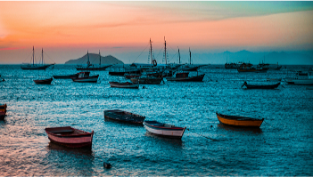 Boats resting on calm blue water at sunset.