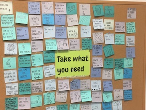 A corkboard full of pinned sticky notes, where each sticky note has a short, inspirational message.