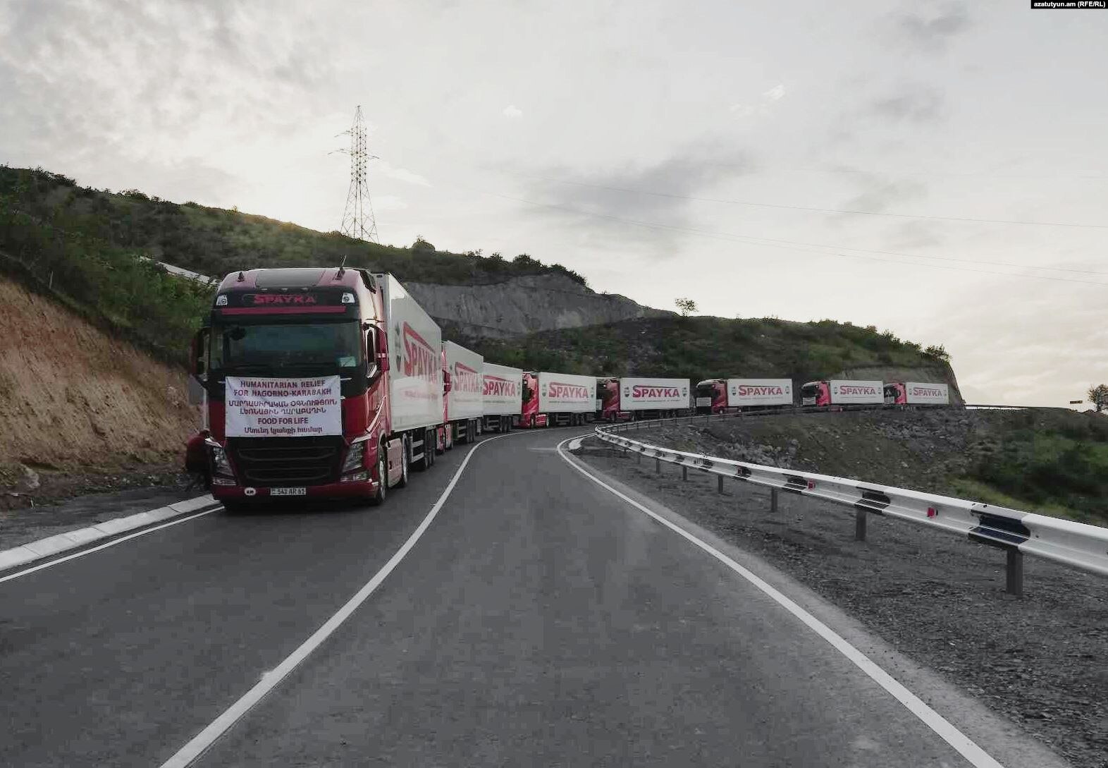 A convoy of eight Armenian trucks carrying humanitarian aid is seen stalled on a roadway just before the Lachin Corridor checkpoint.