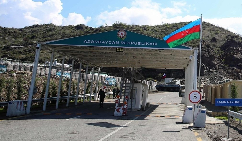 The Lachin Corridor checkpoint, with an Azerbaijani flag and military personnel.