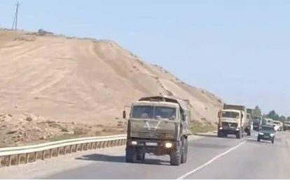 A convoy of Azerbaijani military vehicles—all marked with an emblem resembling an upside-down capital letter A—is seen transporting soldiers to the border.