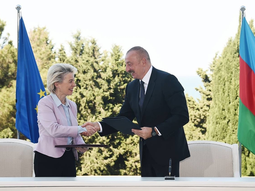 Ursula von der Leyen shakes hands with President Aliyev. Behind them are the flags of the EU and Azerbaijan, respectively.