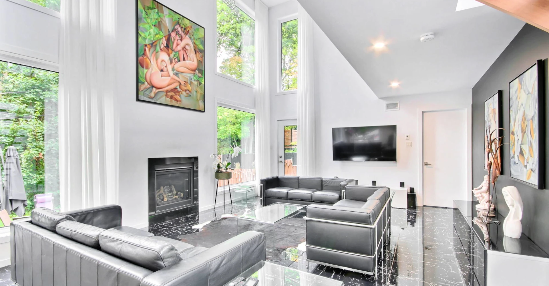 Salon aire ouverte avec grandes fenêtres panoramiques sur la forêt