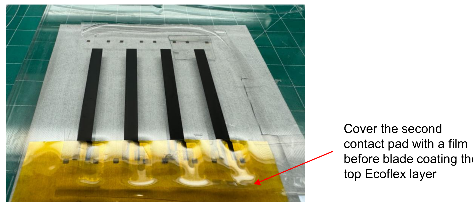 Photo of the sensor strips with the top Ecoflex mask in place, showing where the second contact pad should be covered with film before coating