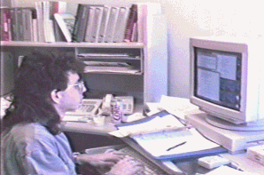 Retro photograph of Todd sitting in front of a computer with a mullet hairstyle.