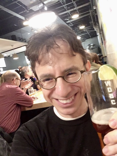 Image of todd holding up a pint of beer and smiling.