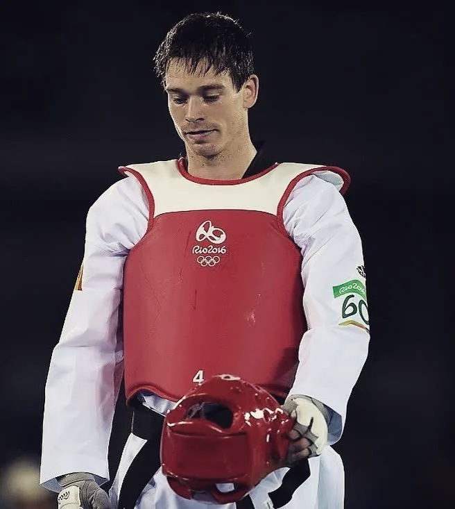Aaron Cook, head bowed, holding his headgear before competing