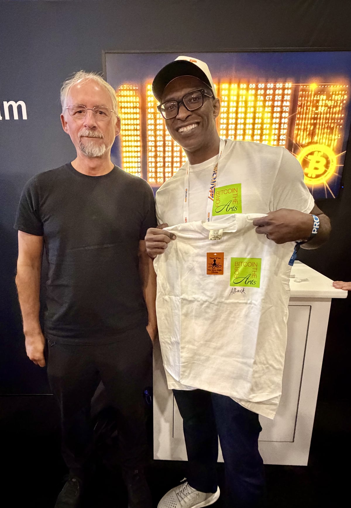 Adam Back signing a Bitcoin for the Arts shirt with Dion Wilson