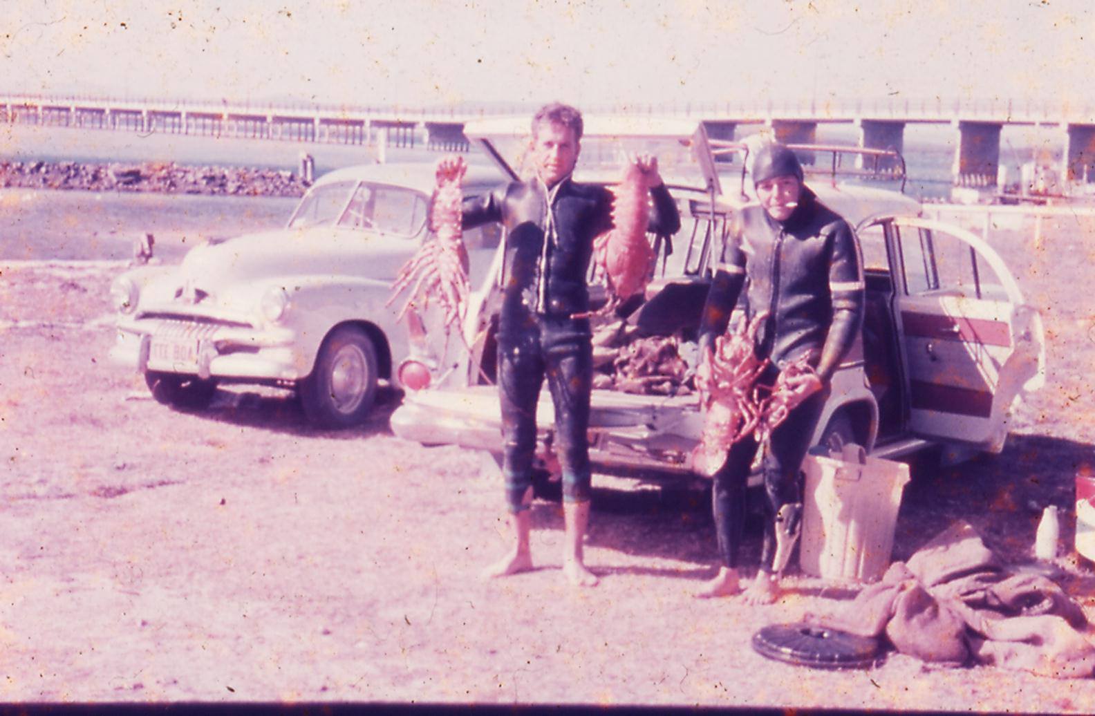 Vintage NSUC divers showing their catch by classic cars