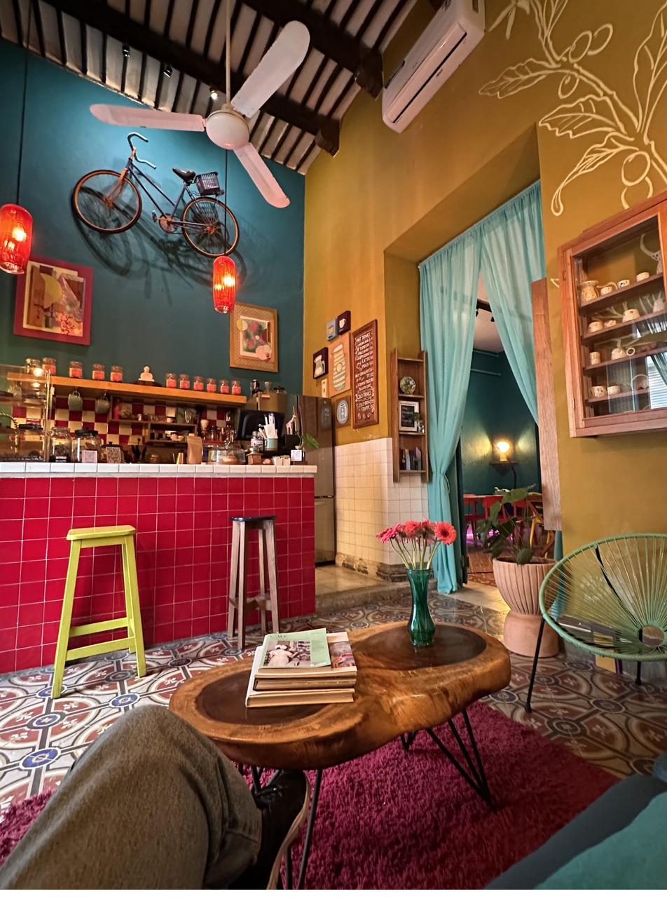 Barra roja de azulejo, bancos amarillos y bicicleta colgada sobre muro azul