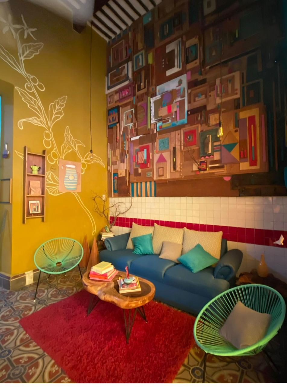 Sala de LA 60: sillones, mesa de tronco y el muro de marcos ensamblados al fondo