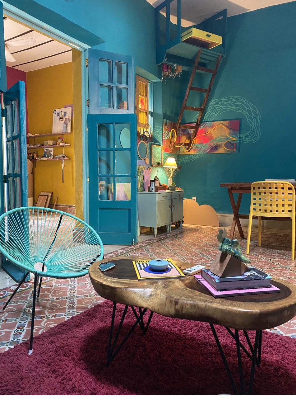 Sala azul con puertas antiguas, silla acapulco turquesa y piso de pasta