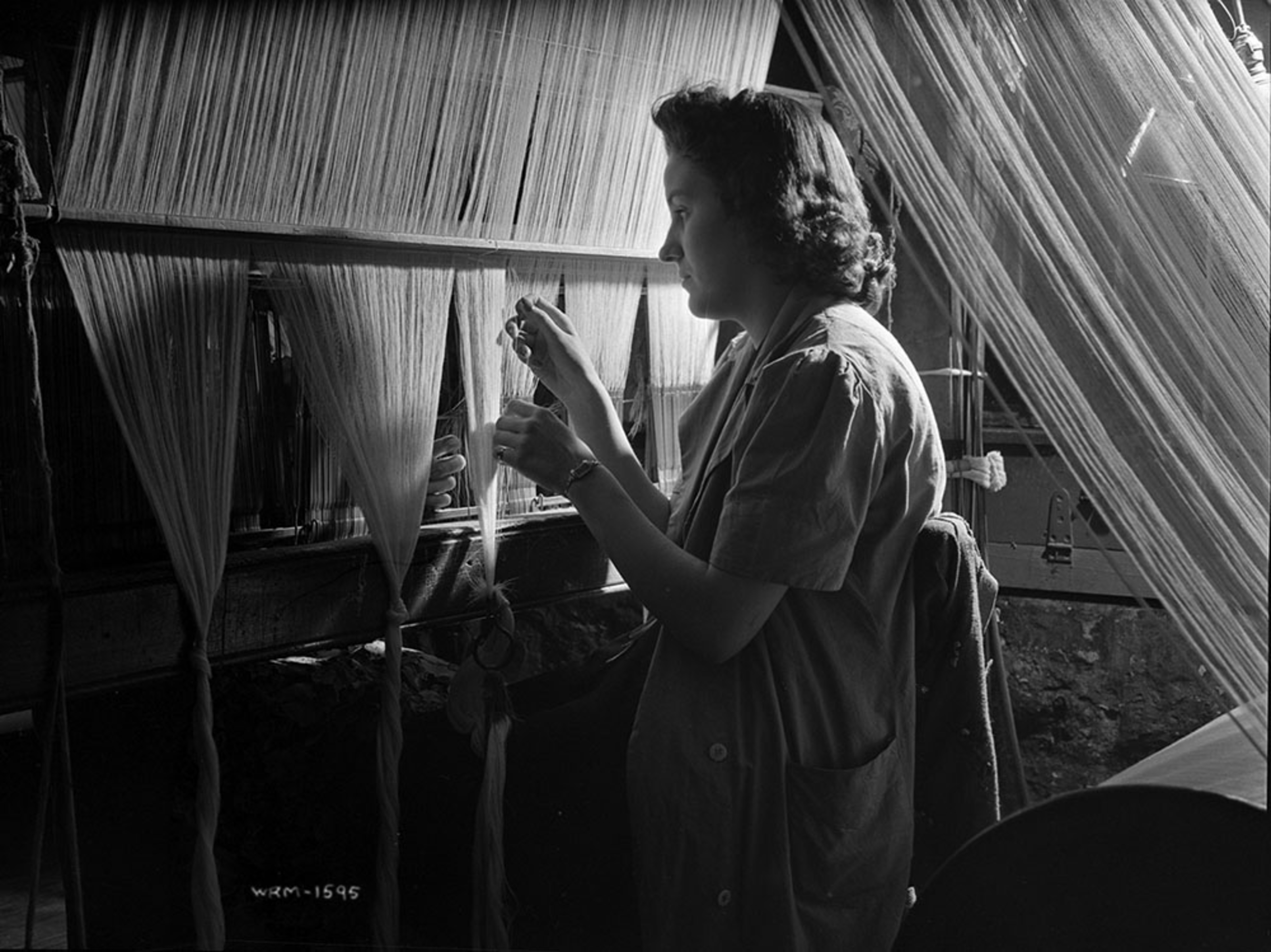 Hélène Lalonde drawing in ends at a loom, Montreal Cottons, Valleyfield.