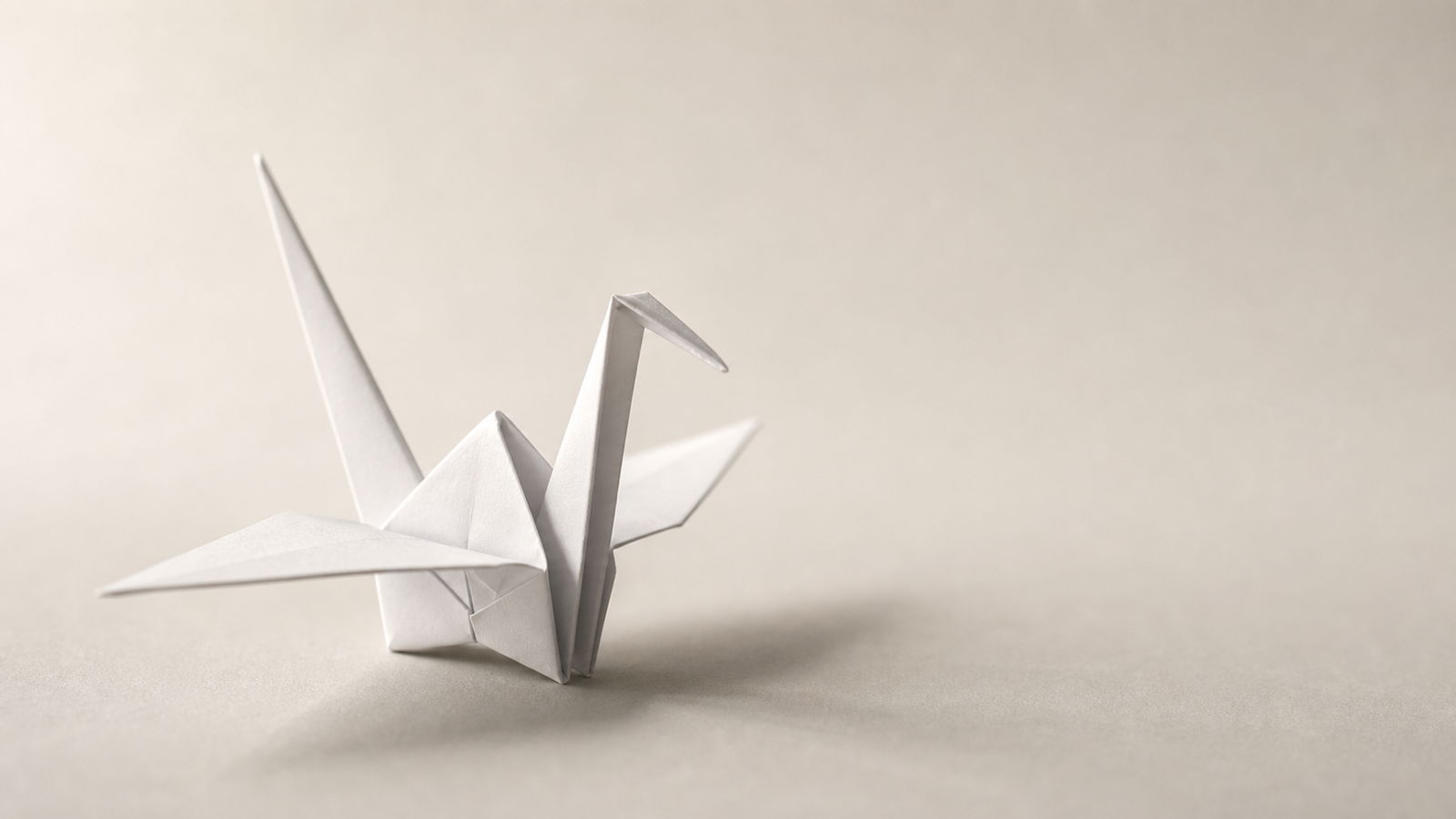 A single white origami crane on a soft warm-gray surface — sample output generated by gpt-image-2 via this skill