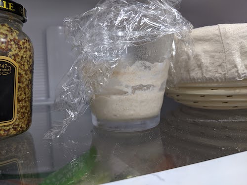 about 3 spoonfulls of starter in a transparent glass in the fridge