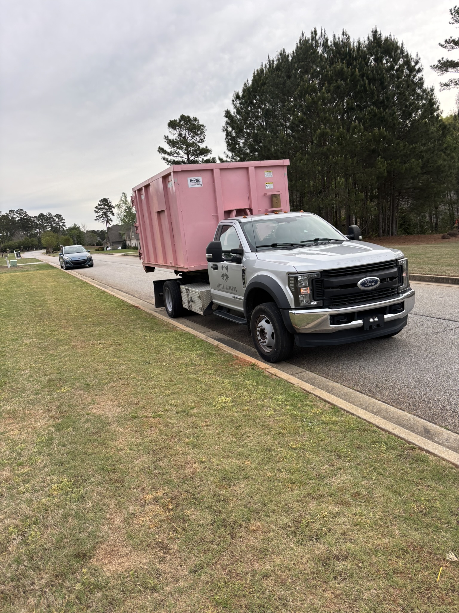 21-yard pink dumpster loaded on specialized hook-lift delivery truck