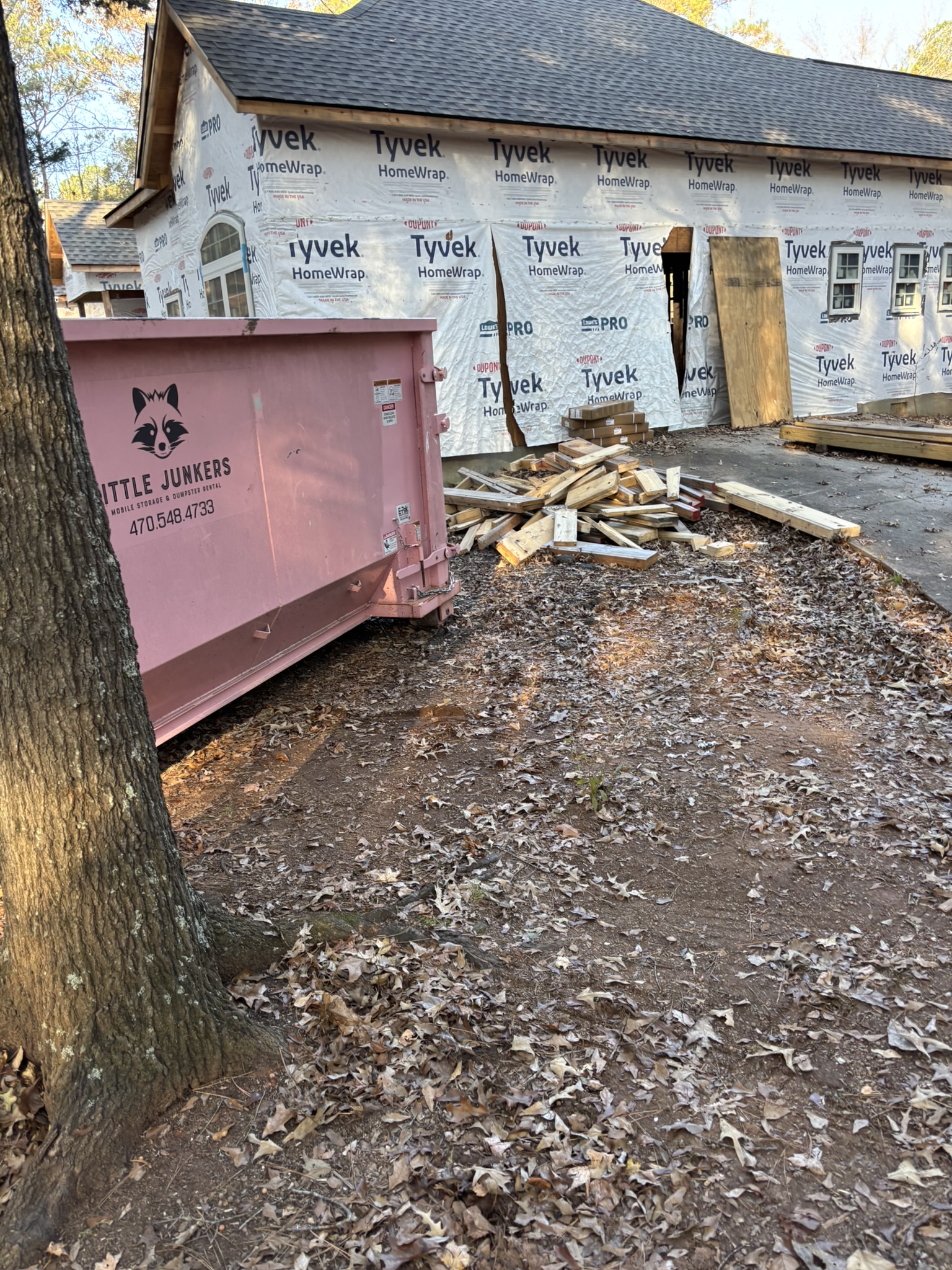 Pink dumpster sitting outside active home renovation site