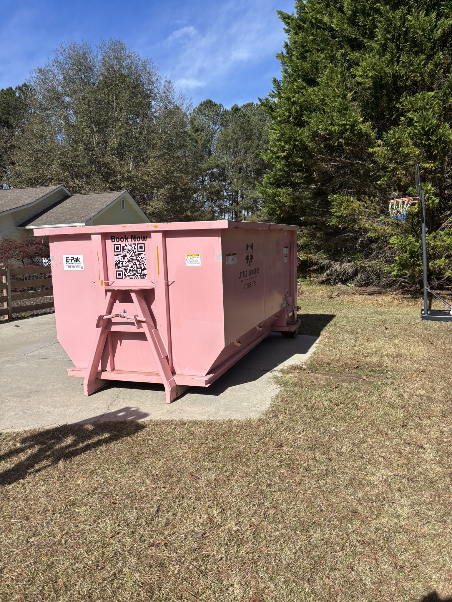 16-yard pink roll off dumpster on sunny residential driveway