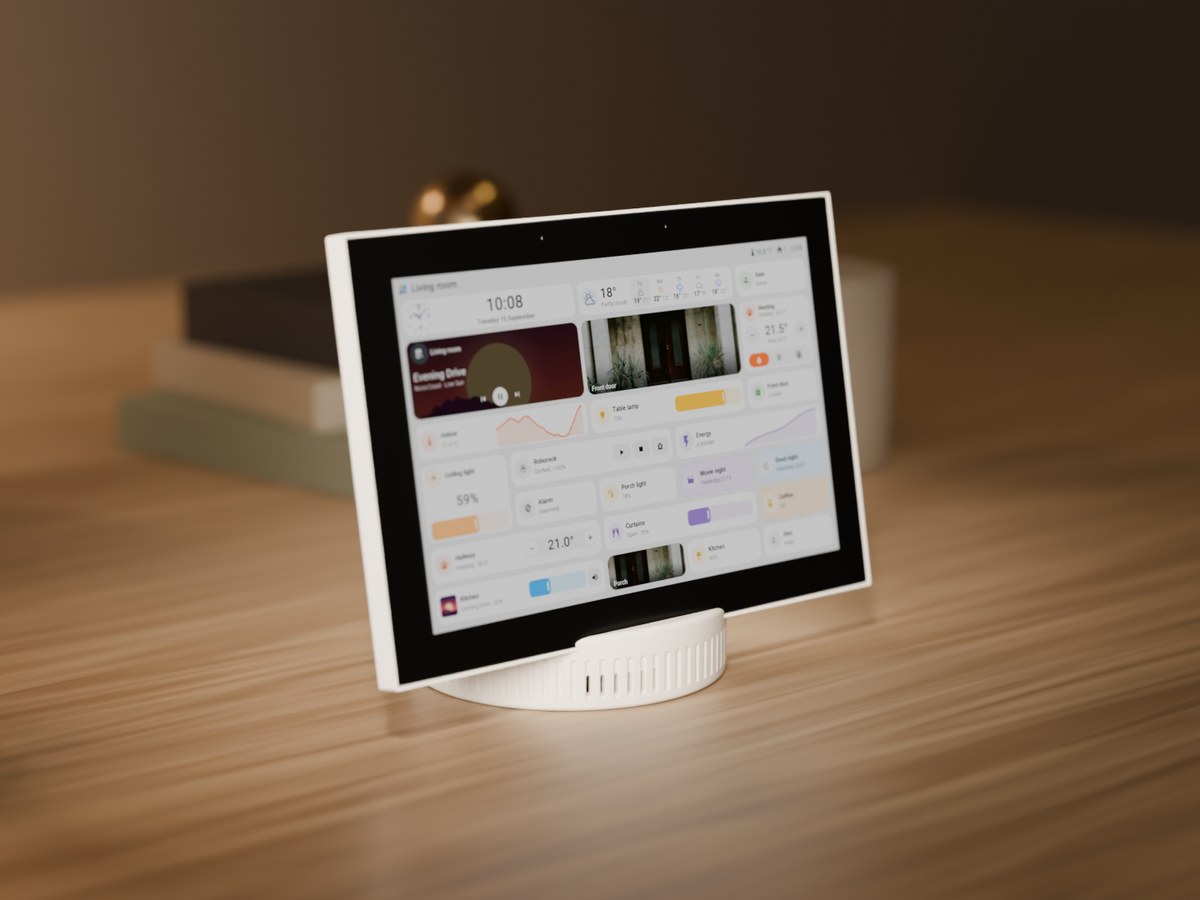 A Seeed reTerminal D1001 on a round white printed base on a wooden desk, showing a Tessera page with the clock, the weather, music, a camera and the lights