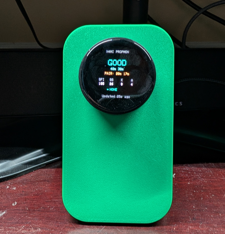 PropMon on 3D printed angled desk stand showing the Overview screen on a LilyGO T-Encoder Pro round AMOLED