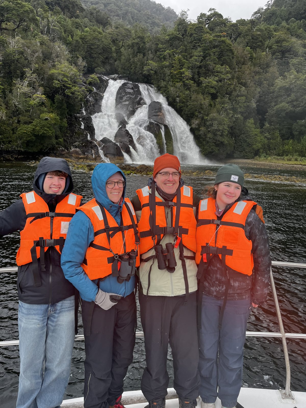 Viajeros navegando frente a una cascada en un fiordo patagónico