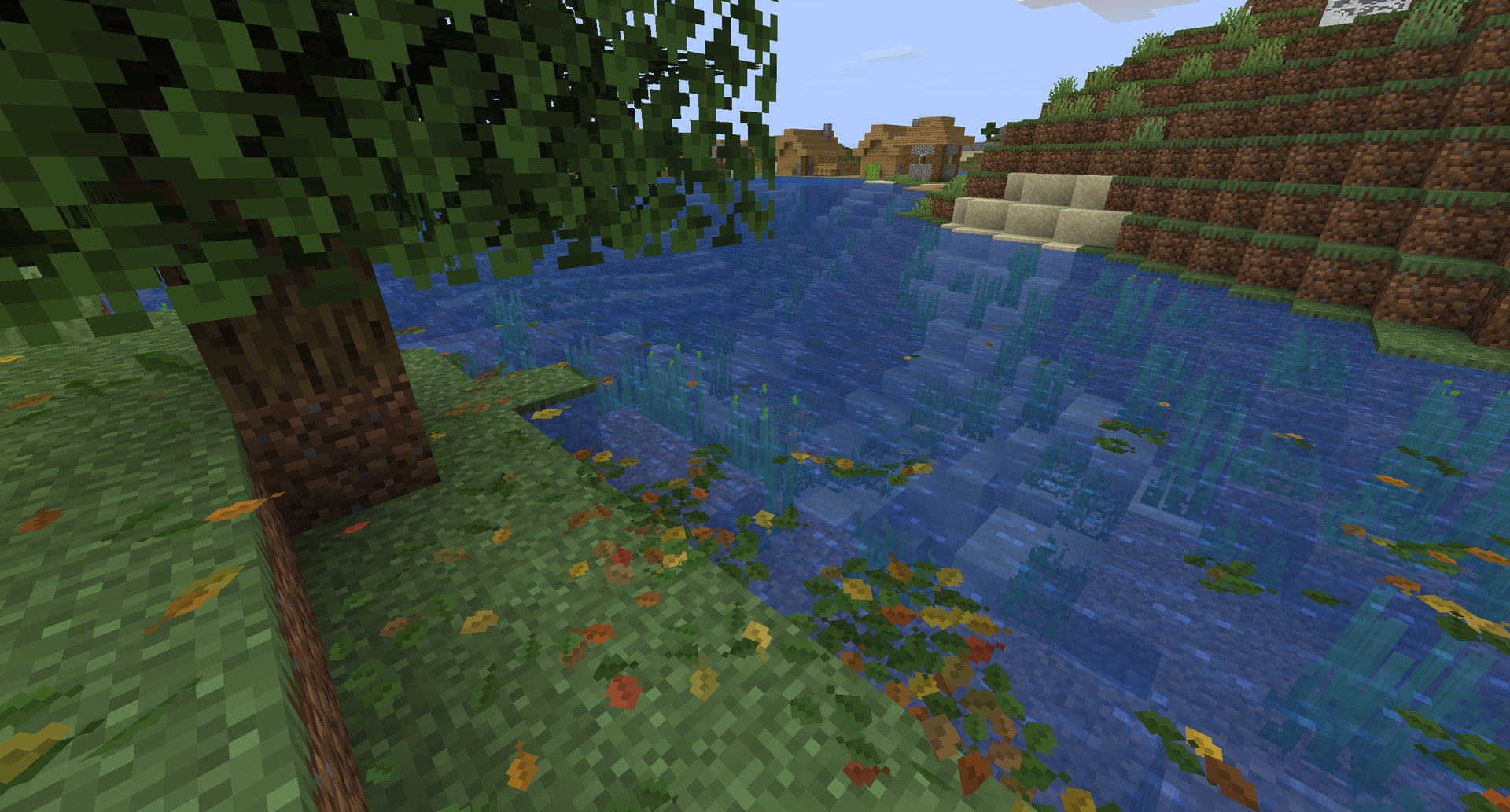 Fallen leaves drifting on a river and lying along its bank