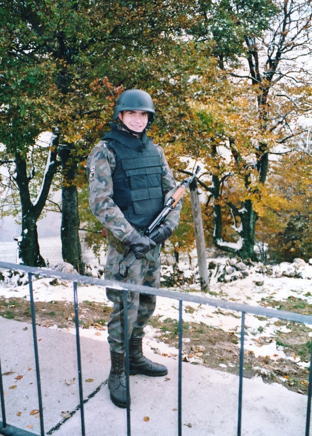 Mitja Močnik med varovanjem vojaškega objekta na Trdinovem vrhu oktobra
                        1992 kot pripadnik oddelka poklicnih vojakov 6. pokrajinskega štaba Nova
                        Gorica. Pripadniki Slovenske vojske so na varovanju Trdinovega vrha bili
                        opremljeni s prvimi zaščitnimi neprebojnimi jopiči in čelado izdelano iz
                        kevlarja ameriškega proizvajalca. Na uniformi nosi našitek Samostojne bojne
                        skupine 6. Pokrajinskega štaba za teritorialno obrambo Nova Gorica.