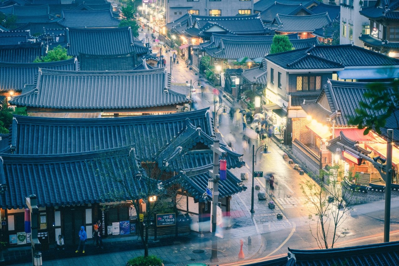 Rain falling over the tiled roofs and lantern-lit streets of Jeonju Hanok Village at dusk — ⓒ한국관광공사 포토코리아-최영락 (Korea Tourism Organization, KOGL Type 1)