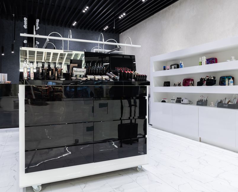 Interior of a cosmetics counter with black display cases and shelving stocked with skincare and makeup products