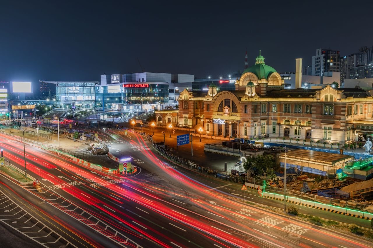 Seoul Station at night, its century-old dome lit gold above light-trail traffic streaming past the terminal