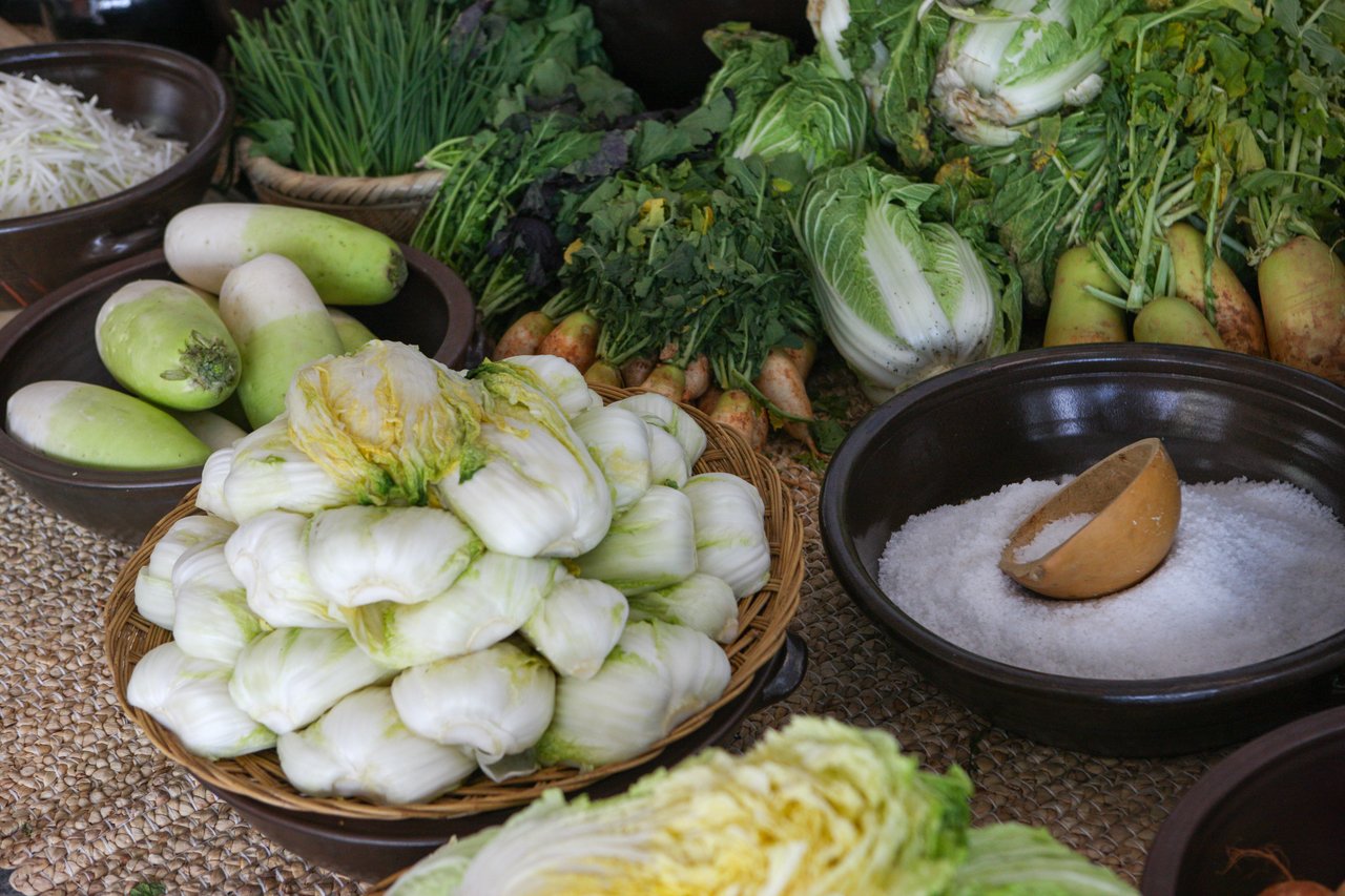 Napa cabbage, radish, scallions and coarse salt laid out for kimchi prep in traditional bowls — ⓒ한국관광공사 포토코리아-김지호 (Korea Tourism Organization, KOGL Type 1)