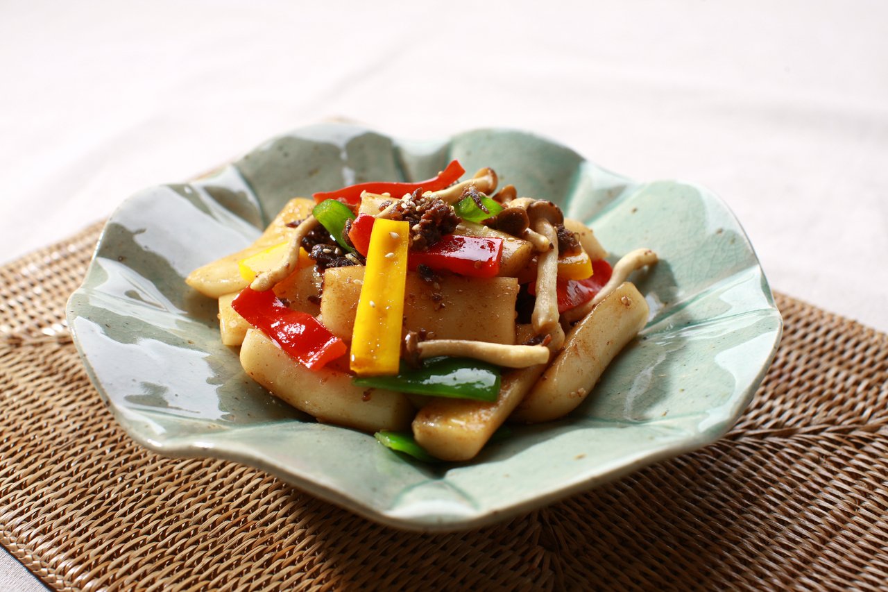 A bowl of savory soy-glazed rice cakes with bell peppers and mushrooms, the non-spicy gungjung tteokbokki style — ⓒ한국관광공사 포토코리아-김지호 (Korea Tourism Organization, KOGL Type 1)