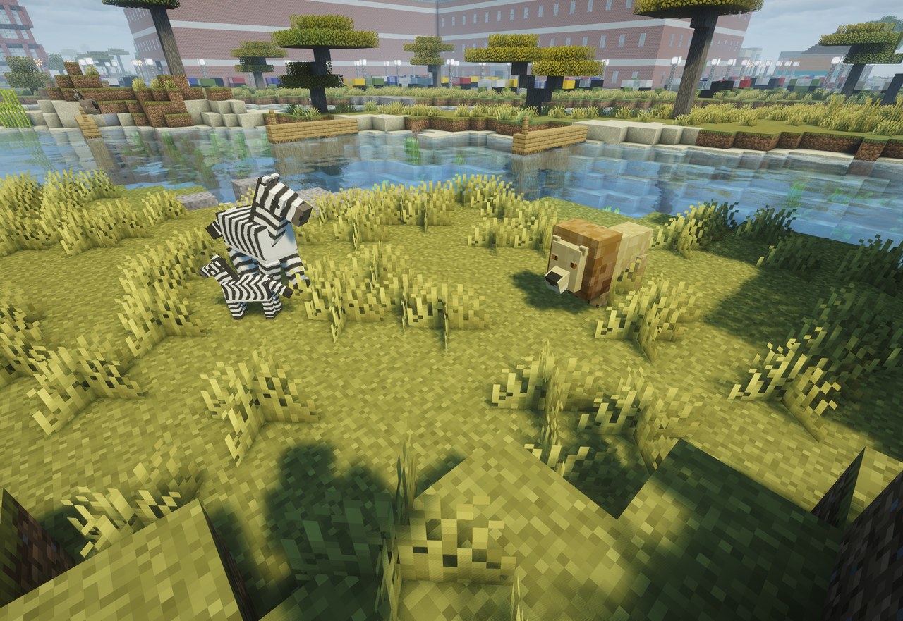 A lion in the grass by a river, a zebra grazing a few blocks away
