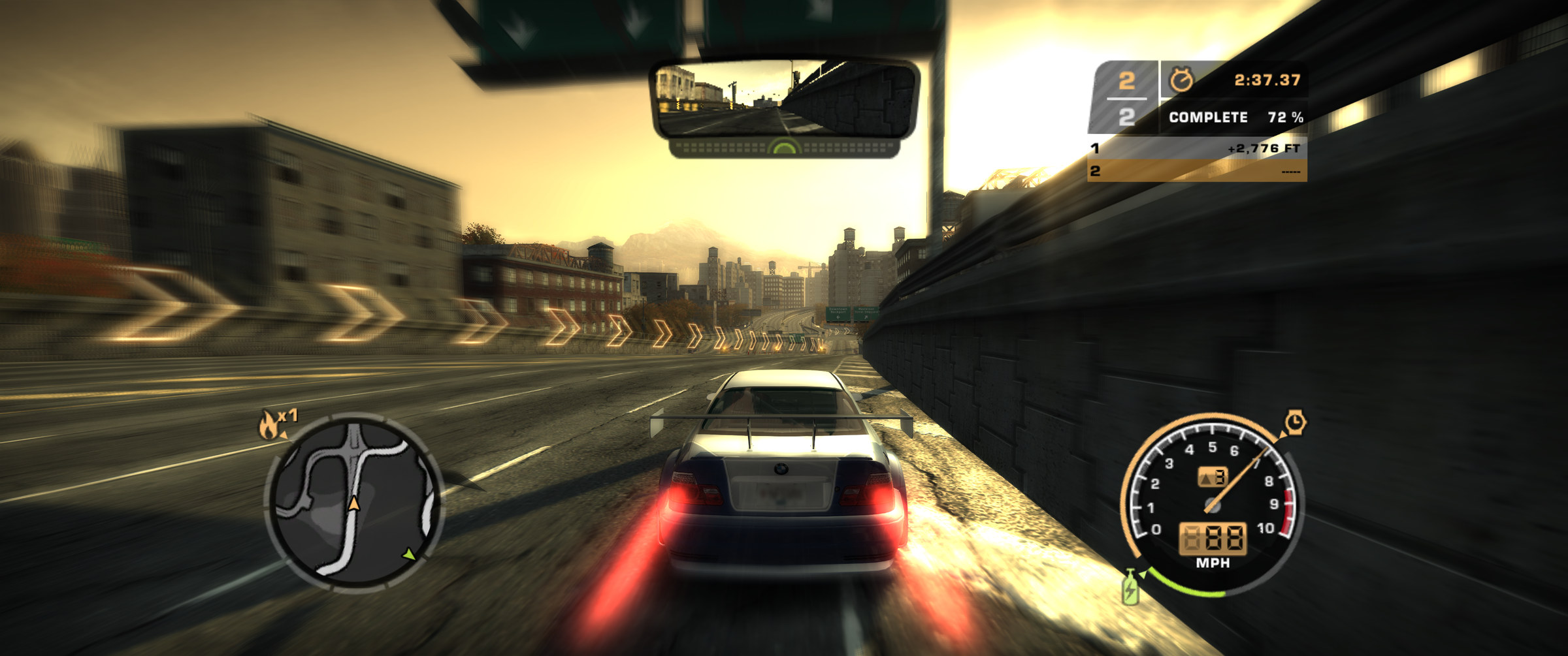 A race on a 21:9 ultrawide screen, seen from the camera behind the player's car: an open expressway into a low sun, with the race HUD and the rear-view mirror