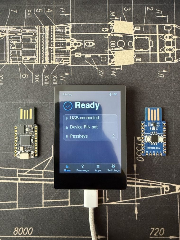 Three RS-Key boards on a blueprint background: a bare RP2350 USB stick, the trusted-display variant showing its Home "Ready" screen (USB connected, Device PIN set, 2 passkeys), and a Waveshare RP2350-One