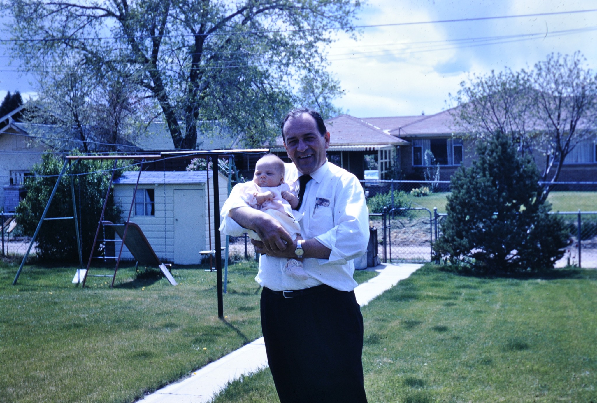 Robert Norton holding his granddaughter Pamela Norton as a baby in a family backyard