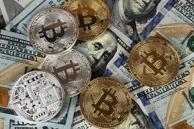 Gold and silver Bitcoin coins on $100 bills