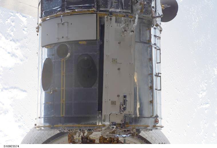 Hubble Space Telescope photographed against Earth's cloud cover after the STS-109 servicing mission, with the new power-control assembly visible.