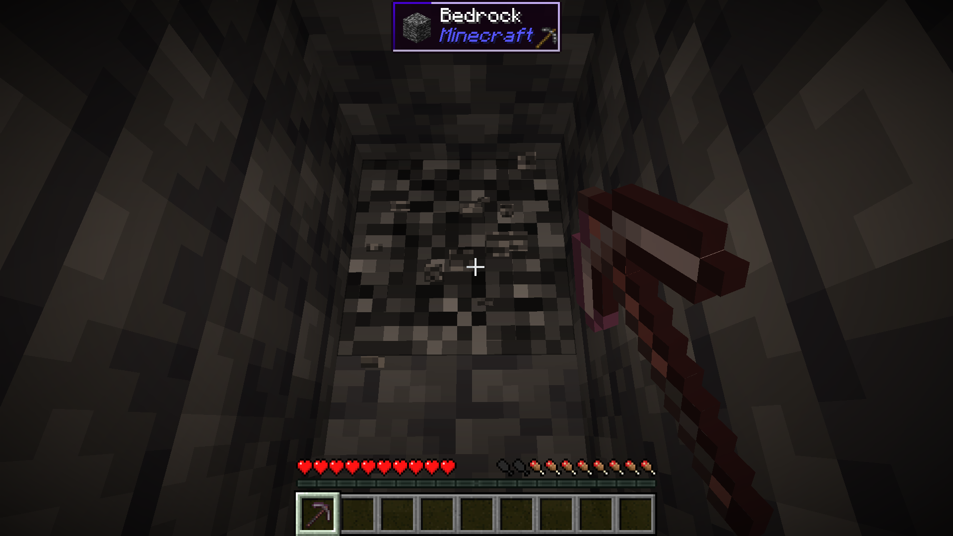 A Netherite Pickaxe mining a Bedrock block.