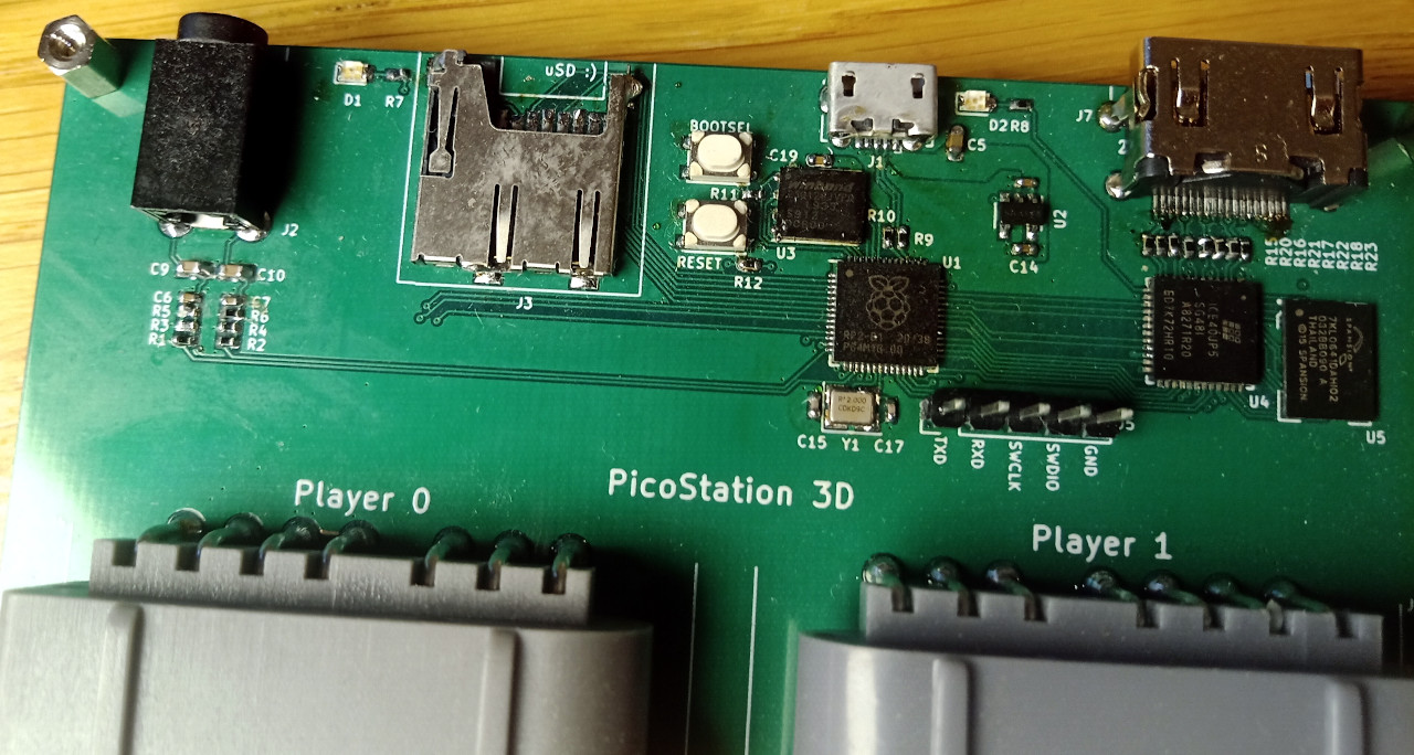Top detail of a prototype board, showing the RP2040 microcontroller, iCE40 UP5k FPGA, and HyperRAM. The controller ports are labelled player 0 and player 1.