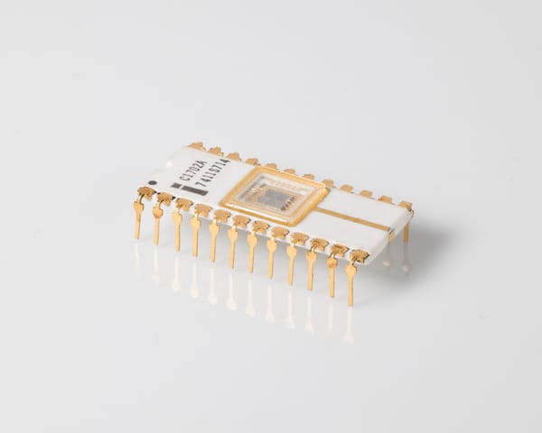 Intel C1702A EPROM, three-quarter view: white ceramic 24-pin DIP, quartz window over the die, 'C1702A 7411S714', gold pins