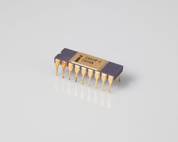 Intel C8008-1 processor, three-quarter view: purple ceramic 18-pin DIP with a gold lid marked 'i C8008-1 2694A', gold pins