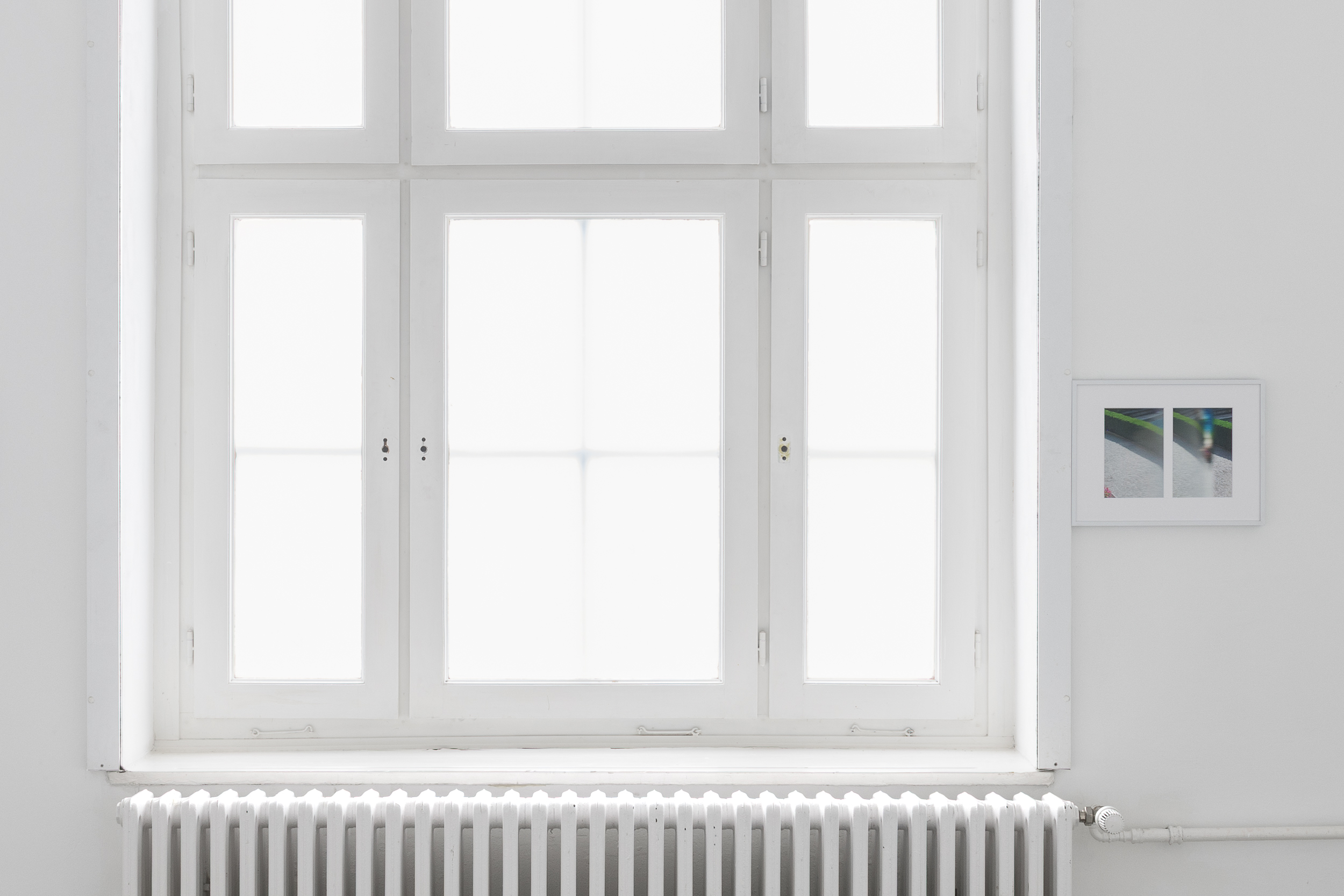 Aisha Altenhofen, The Carrier at UdK Berlin: Close-up of a photograph mounted edge to edge to the window frame, with the composition dominated by a translucent, 'buttermilked' glass texture of the window.