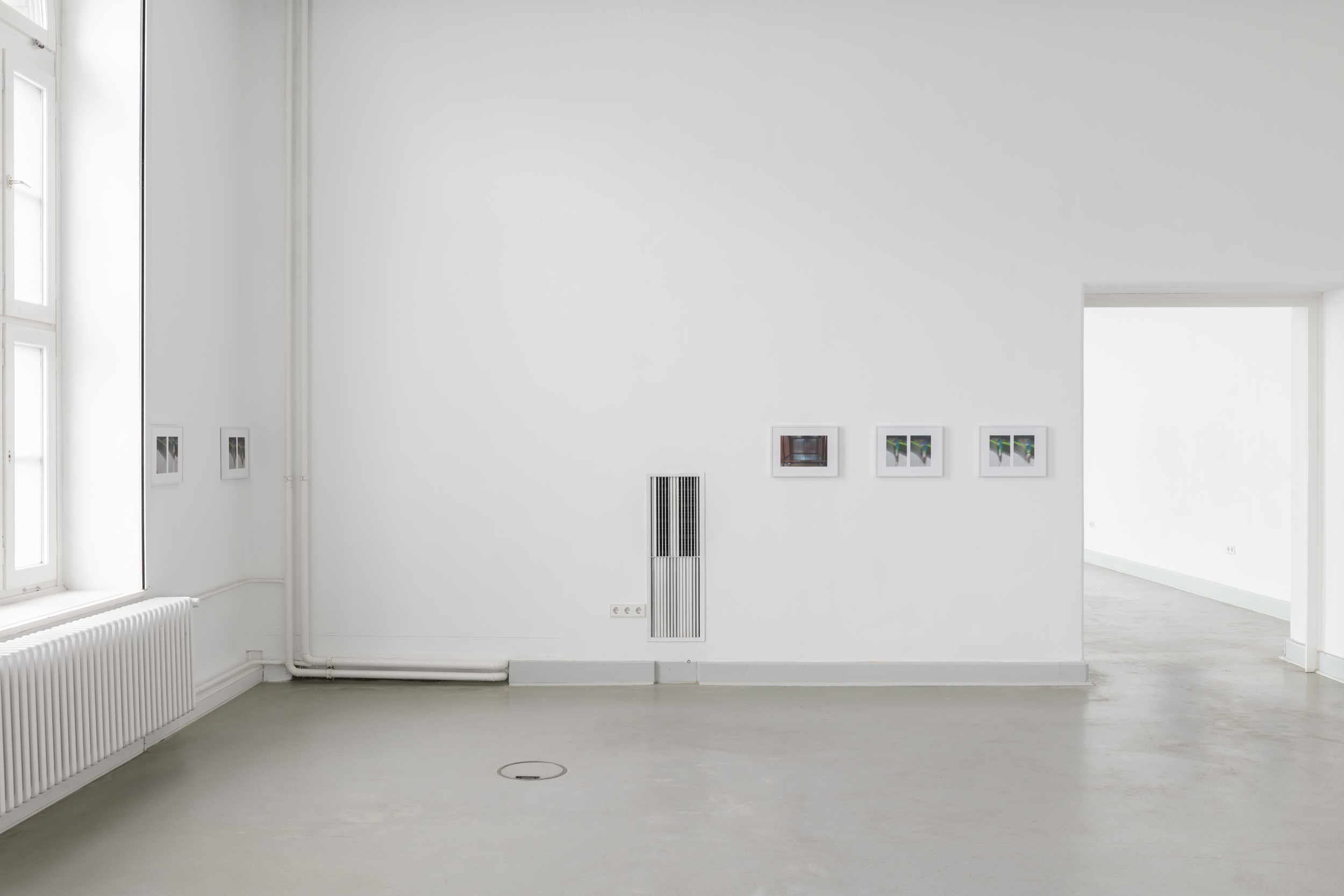 Aisha Altenhofen, The Carrier at UdK Berlin: Installation view featuring three images hung symmetrically to the right of an industrial ventilation shaft, juxtaposed against an empty wall to the left.