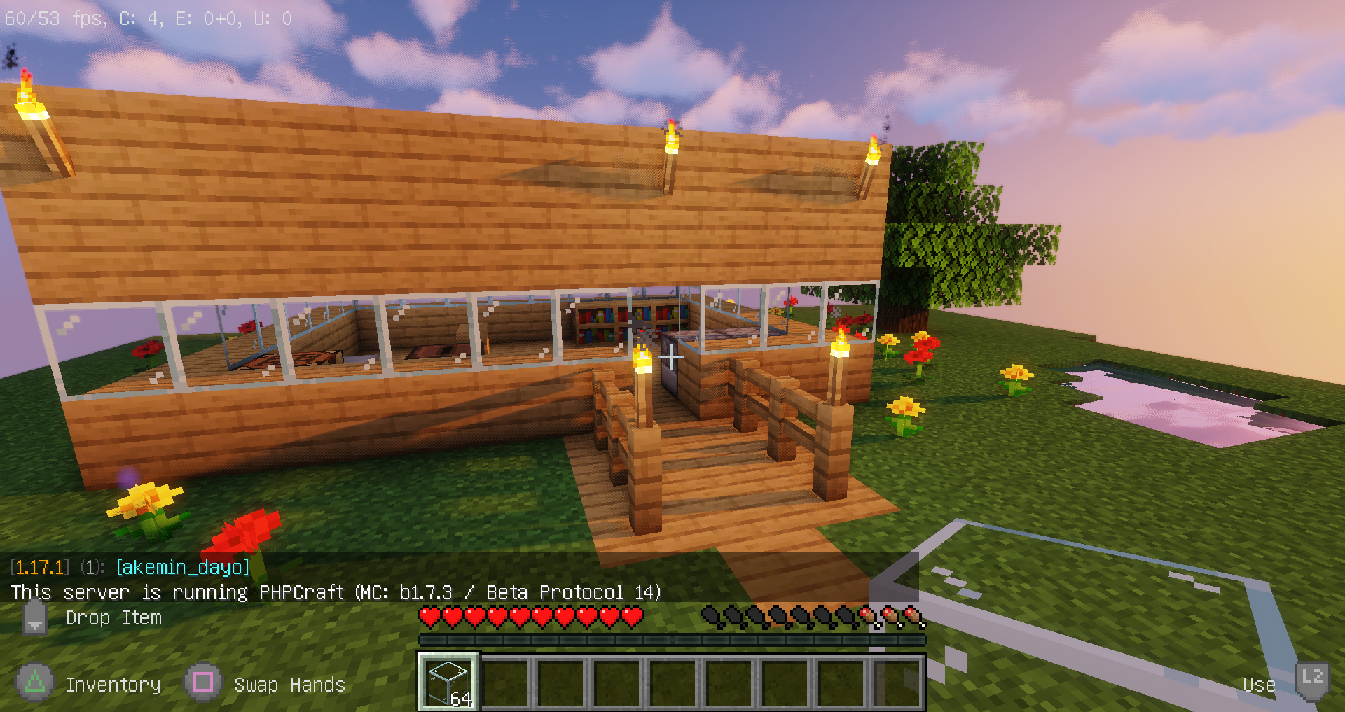 A screenshot of Minecraft 1.17.1 connected to a PHPCraft server, showing a small house that was built from wood planks, a small pond, a tree, and various rose and dandelion flowers scattered about.