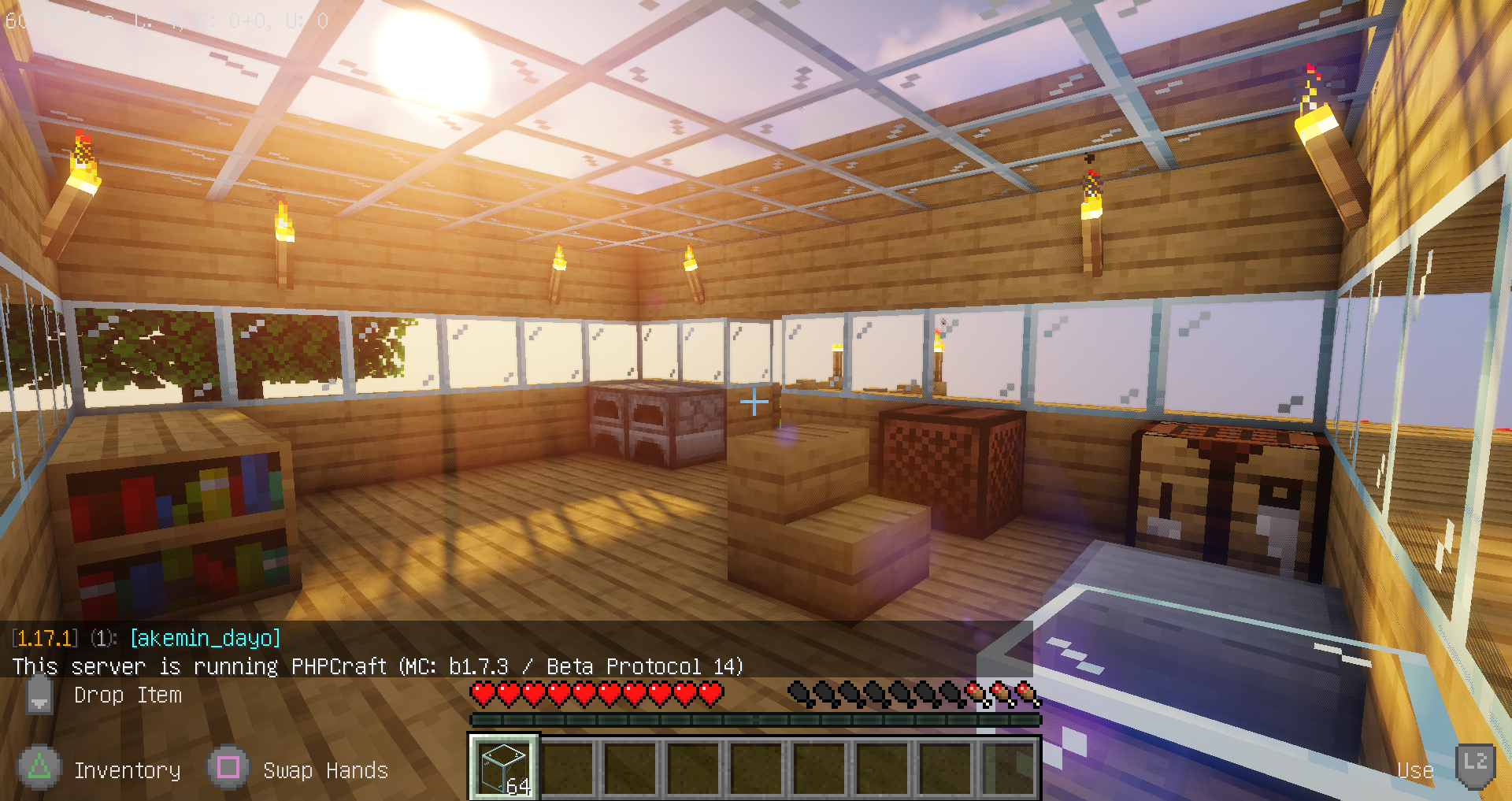 A screenshot of Minecraft 1.17.1 connected to a PHPCraft server, showing the interior of a small house that was built from wood planks. It is later in the day, and the sunlight is filtering through the glass roof. There are two furnaces, some bookshelves, a crafting table, a music player, a chair (actually an oak stair block), and a single stone slab intended to represent a desk.