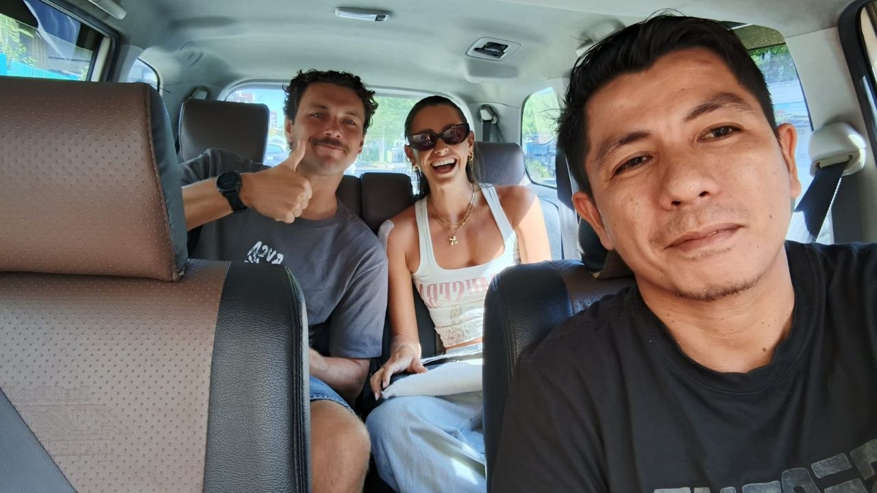 Pasangan wisatawan tersenyum naik FF Taxi Sumbawa