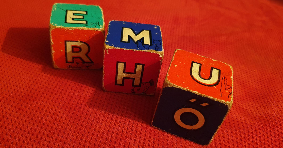 a photo of three wooden cubes with different letters on each face