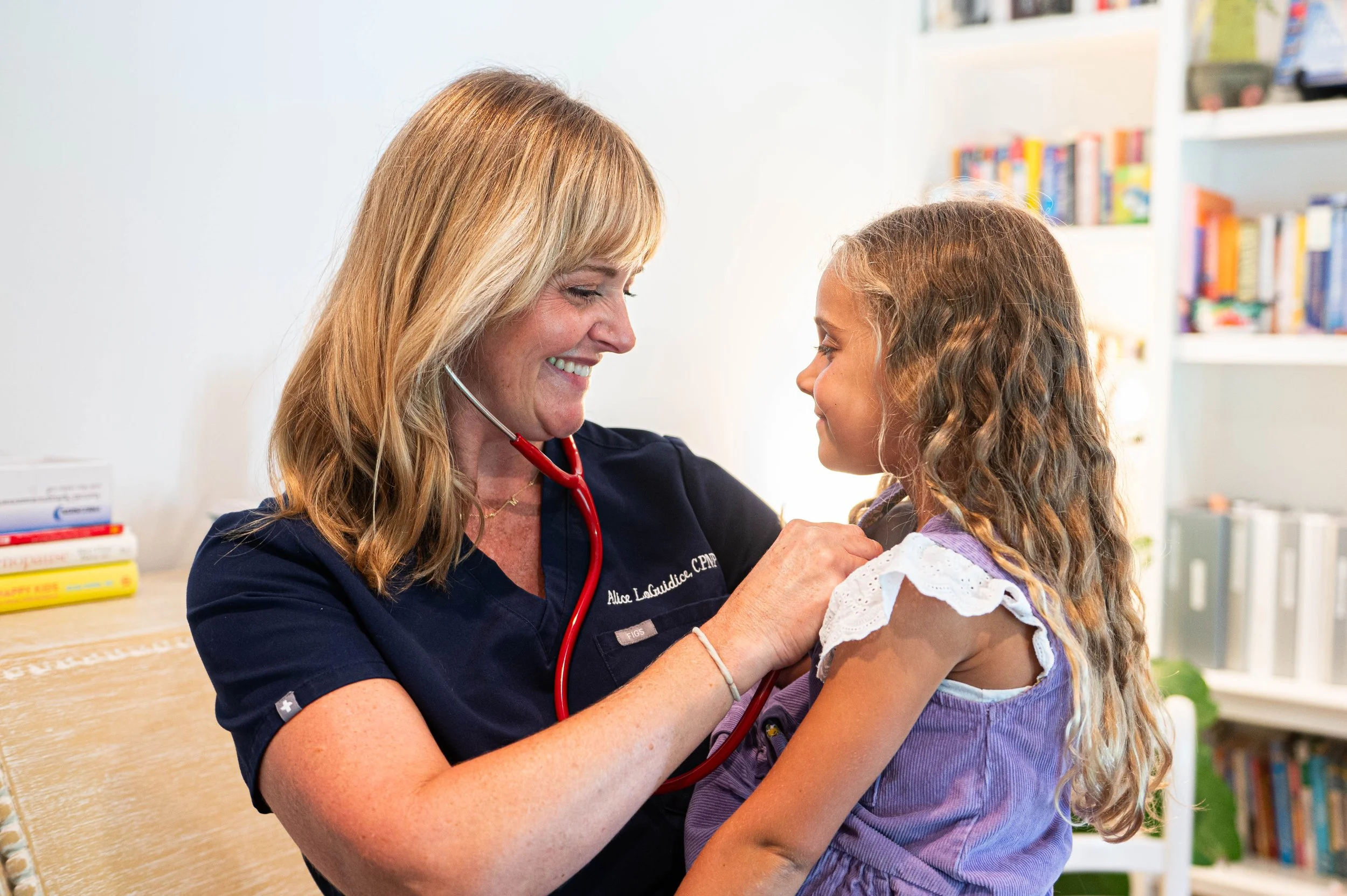 Alice examining a young girl with a stethoscope